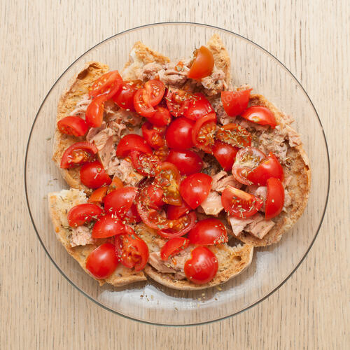 Dried bread called freselle with tuna and tomatoes on wooden