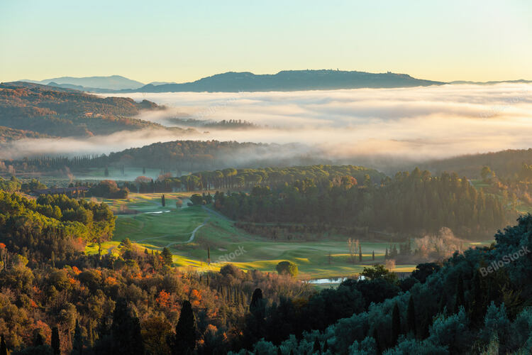 Low lying fog enveloping a picturesque golf course while colorful trees bask in the warm glow of sun