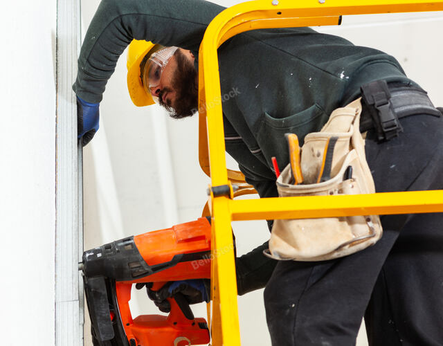 Worker at work in the construction of a plasterboard wall.