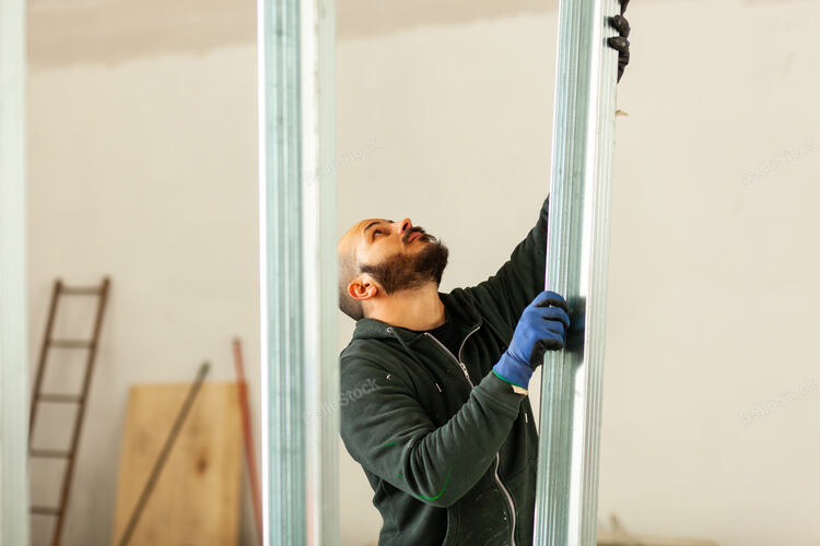 Worker at work in the construction of a plasterboard wall.