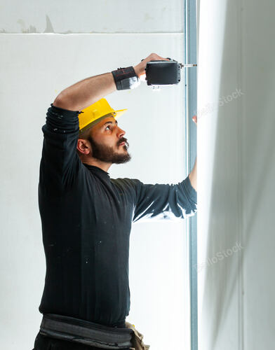 Worker at work in the construction of a plasterboard wall.