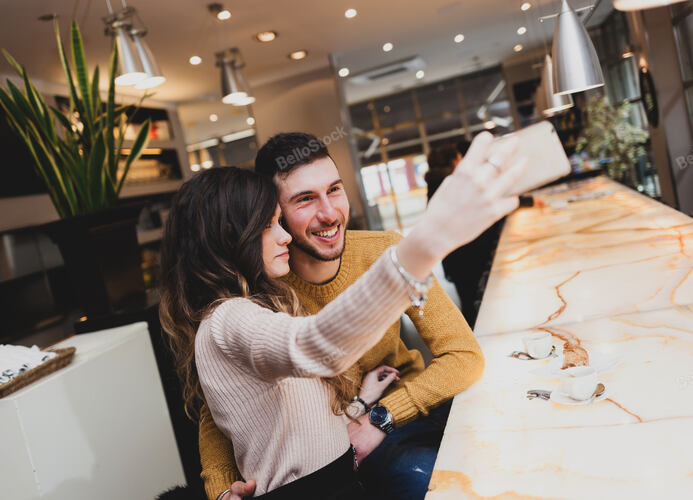 Beautiful young couple at the bar taking a selfie with mobil