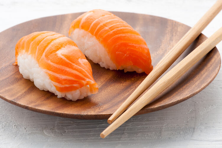 Two fresh salmon Nighiri sushi on a wooden plate with chopst