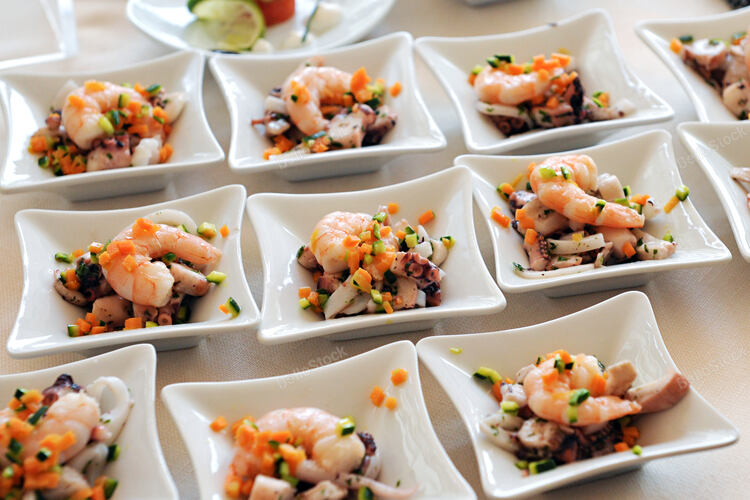 Individual white square plates with shrimp, octopus and cala