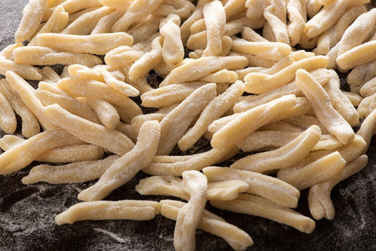 Close up of a pile of uncooked handmade speciality caserecce Italian pasta on a 
