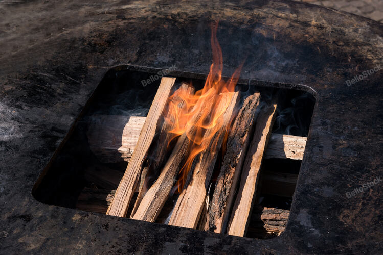 Logs on a barbecue fire beginning to burn in a high angle vi