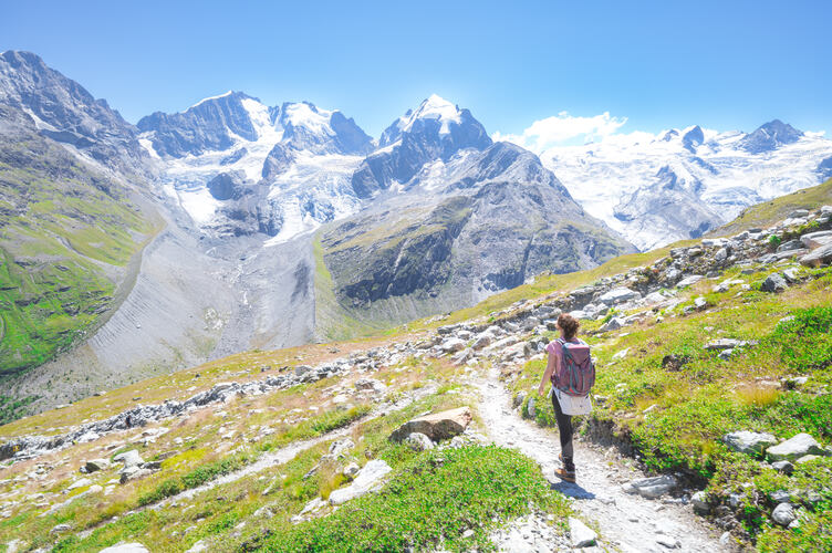 A woman alone walks on high mountain trail in the Swiss Alps