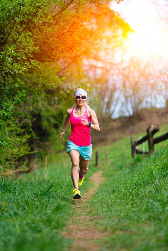 Girl athlete runs into the forest and meadow