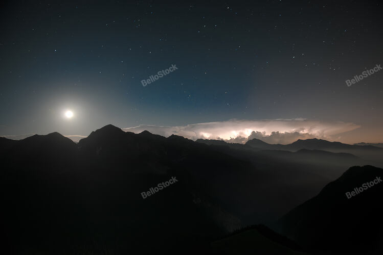 In the night, lightning iin the lower valley, with a starry 