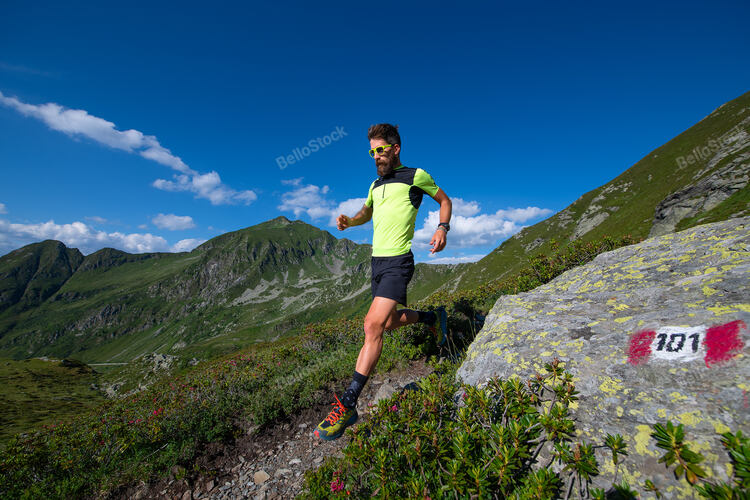 Male athlete practicing mountain running on a trail downhill. — stock photo