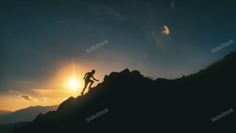 Silhouette of a man climbs a rocky ridge in the mountains in