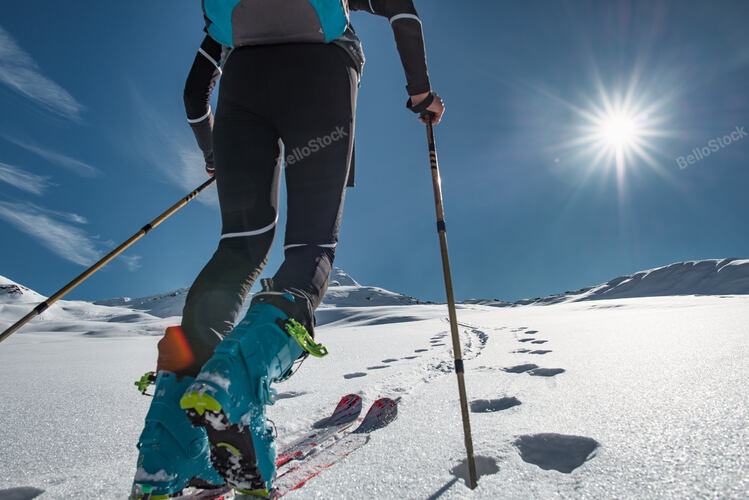 Ski mountaineer climbs up a snowy slope with seal-skins