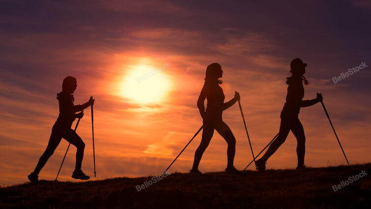 Women do Nordic walking in a red sunset