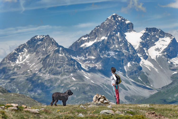 A girl with her big black dog in the mountain takes in the v