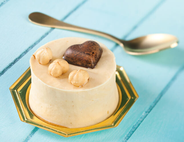 Small cake with hazelnuts and dark chocolate heart on blue w