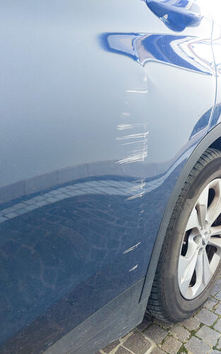Deep scratches and scuffs are damaging a modern blue car par