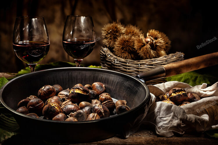 Roasted chestnuts in iron skillet on wooden table.