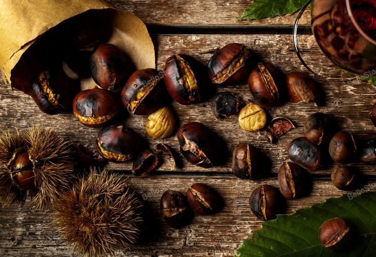 Top view of Roasted chestnuts in paper cone on wooden table.
